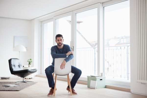 Smart Home: Mann sitzt auf Stuhl im Wohnzimmer